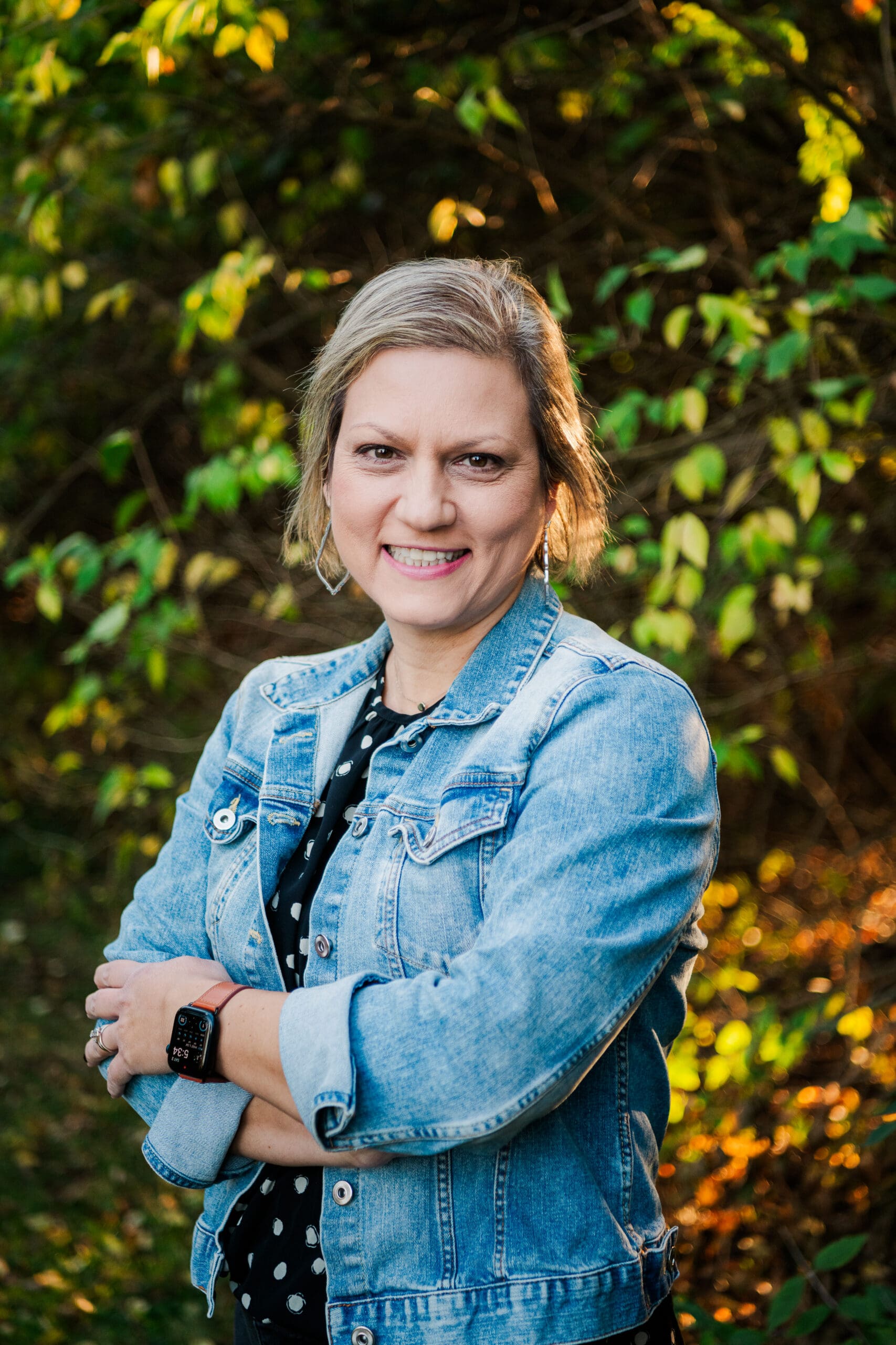 woman with crossed arms smiling at camera taking headshots with darker background